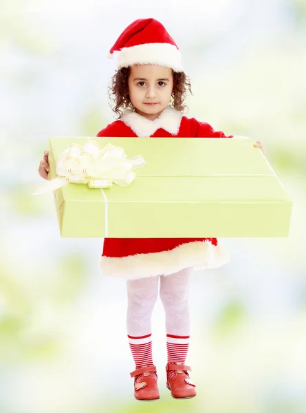 Lille pige i kostume af julemanden med gave - Stock-foto