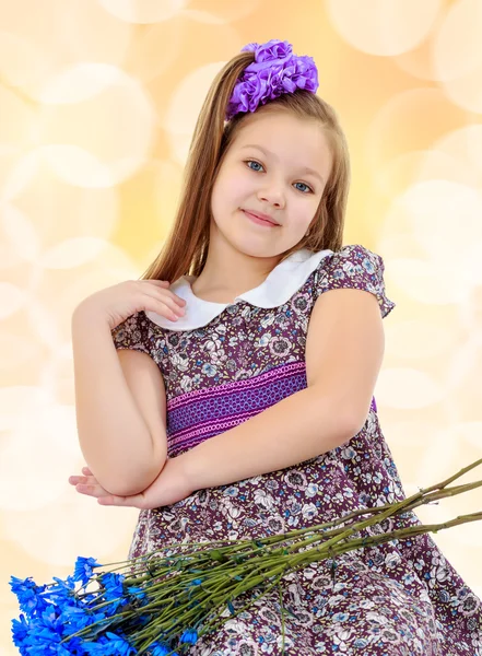 Beautiful little girl with a bouquet of blue flowers — Stock Photo, Image