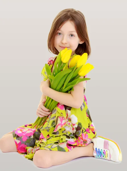 Bambina con un mazzo di tulipani gialli . — Foto Stock