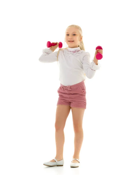 Lille pige laver øvelser med håndvægte. - Stock-foto