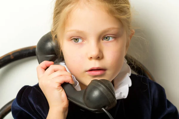 Een klein meisje belt op de oude telefoon.. — Stockfoto
