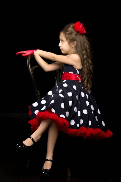 Menina bonita em Polka Dot vestido sentado em fundo preto isolado. — Fotografia de Stock