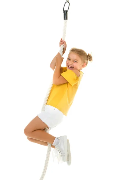 Ein kleines Mädchen hält sich mit den Händen am Seil fest und schwingt sich darauf. — Stockfoto