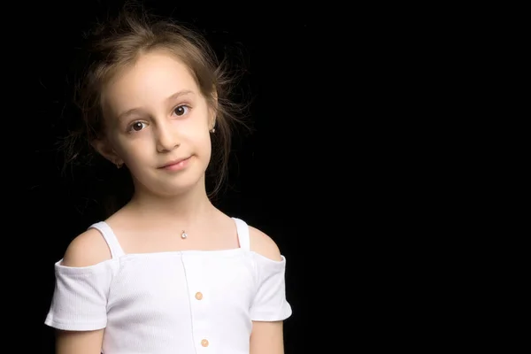 Nahaufnahme eines niedlichen lächelnden kleinen Mädchens, das auf schwarzem Hintergrund posiert. — Stockfoto