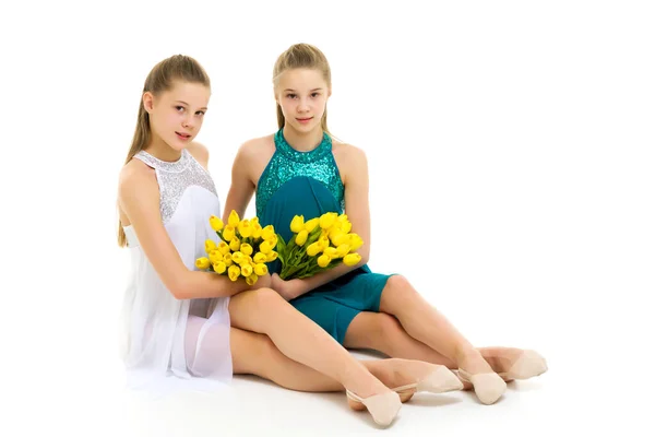 Schöne Mädchen sitzen auf dem Boden mit einem Strauß Tulpen — Stockfoto