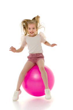 Küçük kız spor olsun diye büyük bir topla oynuyor.