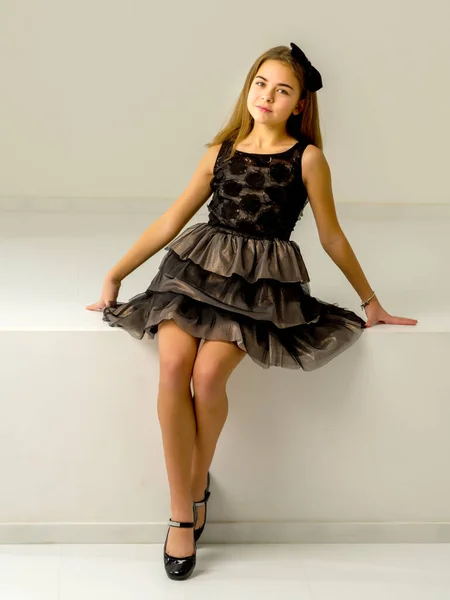 Nettes kleines Mädchen sitzt im Studio auf der weißen Treppe. Stil und Modekonzept, glückliche Kindheit. — Stockfoto