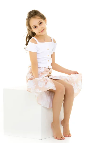 Портрет вдумчивой красивой девушки, сидящей на белом кубе — стоковое фото