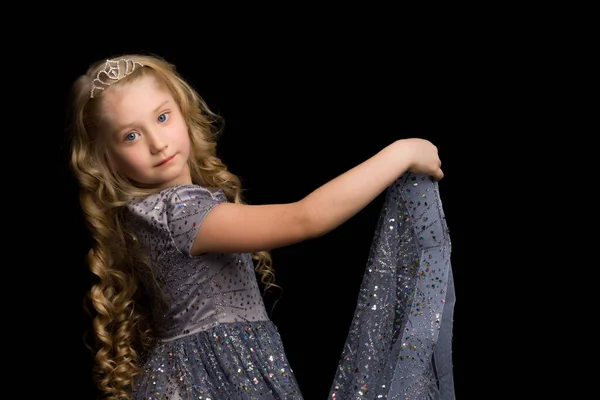 Маленькая девочка в длинном, элегантном платье принцессы на черном фоне. — стоковое фото