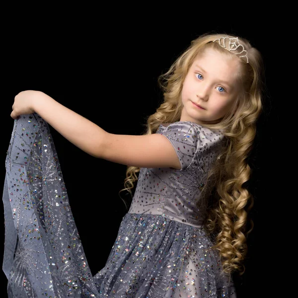 Mała dziewczynka w długiej, eleganckiej sukience księżniczki na czarnym tle. — Zdjęcie stockowe