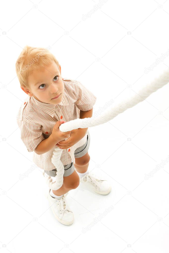 A little boy holds the rope with his hands and sways.