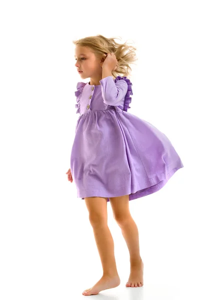 Ein schönes kleines Mädchen steht im Wind, ihre Haare und Kleider entwickeln sich stark. Das Konzept von Stil und Mode. — Stockfoto
