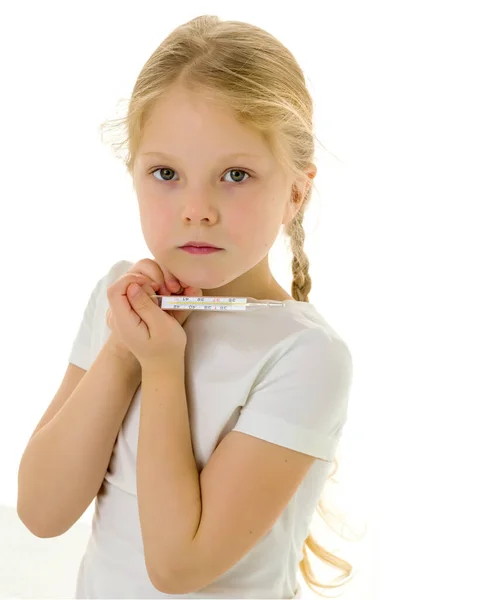 Een klein meisje in een schoon wit T-shirt houdt een thermometer in haar hand. Covid-19 concept, virus, ziekte, behandeling. — Stockfoto