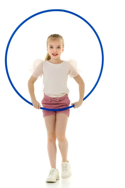 Une petite fille dans un T-shirt blanc effectue des exercices avec un cerceau. — Photo