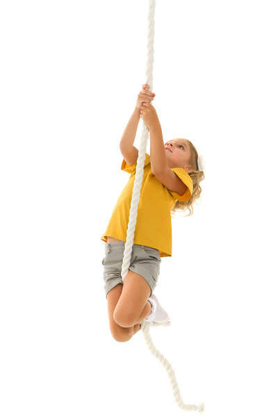 A little girl holds on to the rope with her hands, swinging on it.