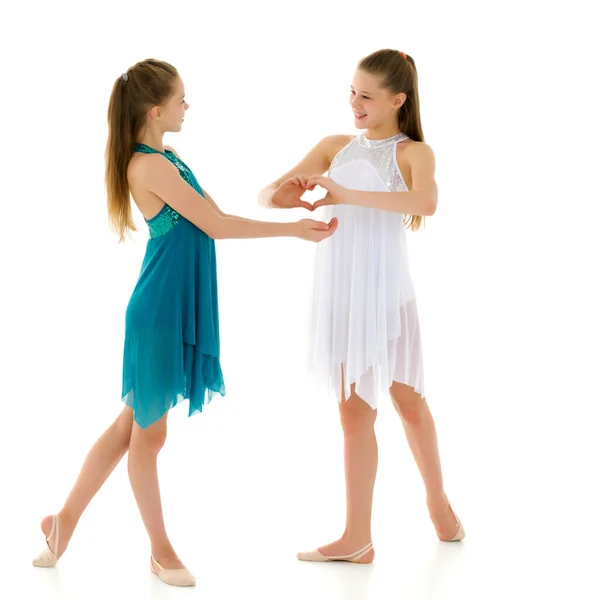 Two adorable girls gymnasts folded palms in the shape of a heart — Stock Photo, Image