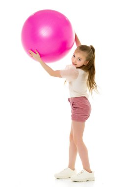 Küçük kız spor olsun diye büyük bir topla oynuyor.