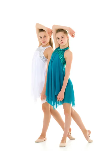 Dos hermanas en vestidos deportivos bailando en estudio sobre fondo blanco. —  Fotos de Stock