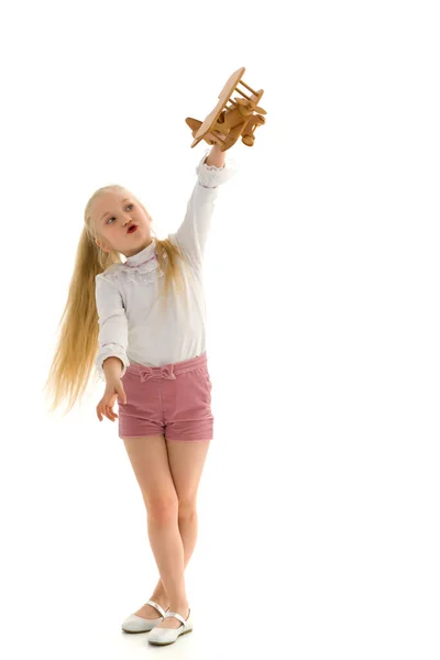 Menina está brincando com um avião de madeira. — Fotografia de Stock