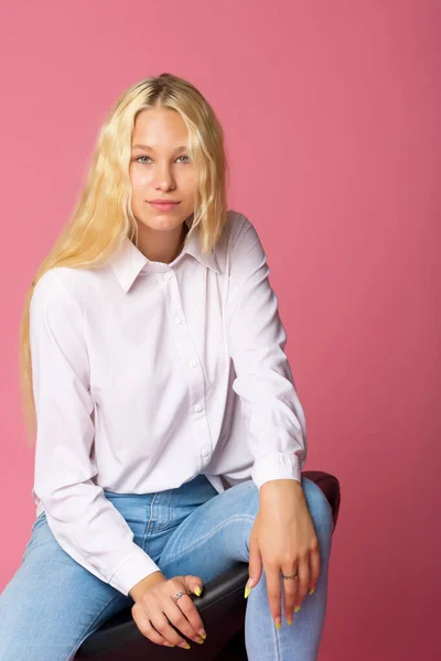 Bonito sorridente loira menina sentada em alta cadeira no estúdio — Fotografia de Stock