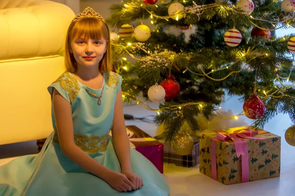 Красивая маленькая девочка улыбается с подарком рядом с елкой — стоковое фото