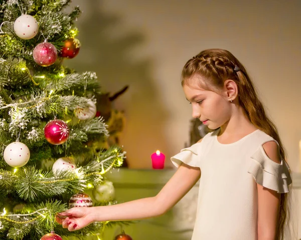 Menina em vestido elegante Sentado no chão na frente da árvore de Natal. — Fotografia de Stock