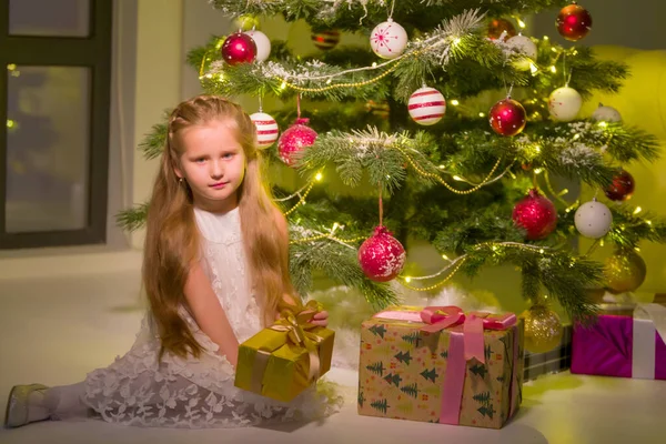 Niña cerca del árbol de Navidad con un regalo. —  Fotos de Stock