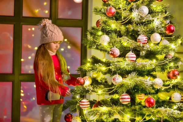 Küçük kız bir Noel ağacını süslüyor. Yeni yıl konsepti, aile tatilleri. — Stok fotoğraf