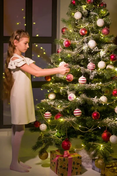 Holčička zdobí vánoční stromek. Nový rok koncept, rodinná dovolená. — Stock fotografie