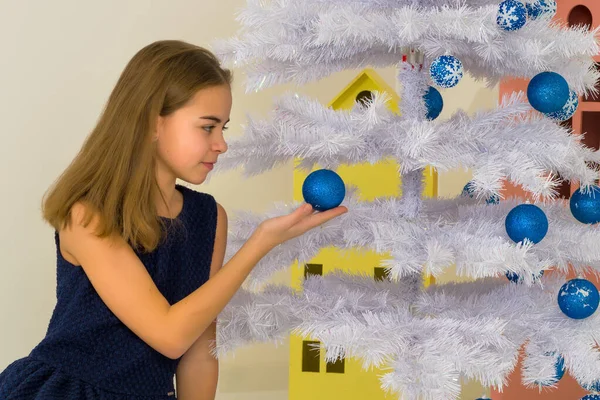 Ragazza in piedi accanto albero di Natale decorato tenendo ramo bianco — Foto Stock