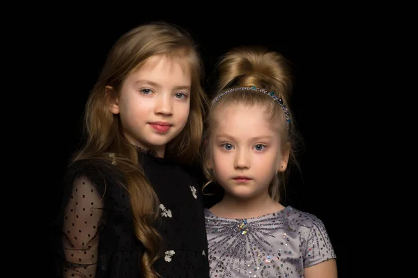 两个小女孩在一个黑色背景的演播室里摆姿势。时尚与时尚概念. — 图库照片