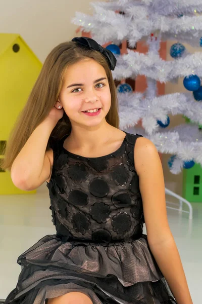 Chica en vestido elegante sentada en el suelo delante del árbol de Navidad —  Fotos de Stock