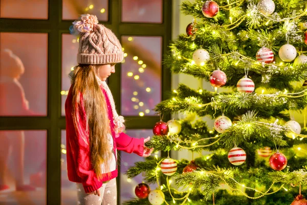 A menina decora uma árvore de Natal. Conceito de Ano Novo, férias em família. — Fotografia de Stock