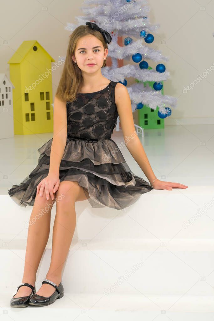 Girl in Stylish Dress Sitting on the Floor in Front of Christmas Tree