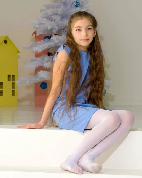 Menina em vestido elegante Sentado no chão na frente da árvore de Natal. — Fotografia de Stock