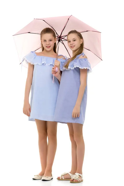 Две симпатичные сестры в одинаковых легких платьях, стоящих под Umb — стоковое фото