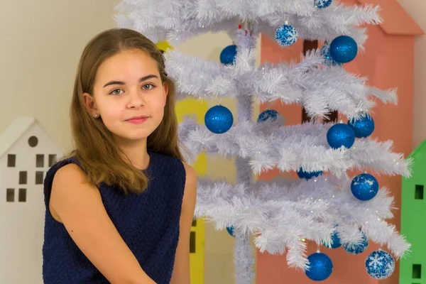 Fille en robe élégante assis sur le sol devant l'arbre de Noël. — Photo