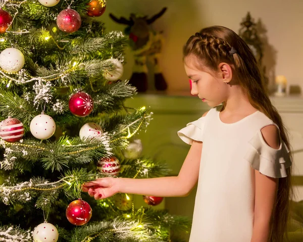 Menina em vestido elegante Sentado no chão na frente da árvore de Natal. — Fotografia de Stock