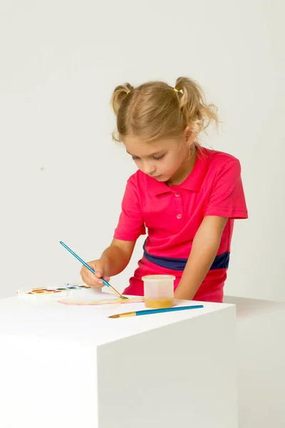 Menina loira bonita em pé na mesa e pintura com aquarela — Fotografia de Stock