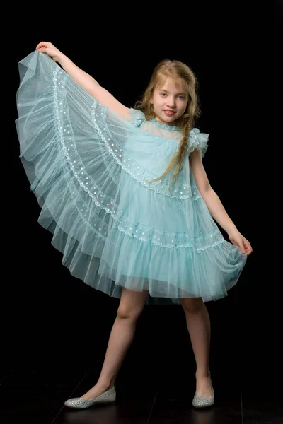 En liten flicka håller sina händer på kanten av kjolen. — Stockfoto