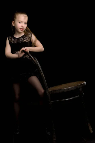 一个女孩站在靠近维也纳旧椅子的黑色背景上的画像. — 图库照片