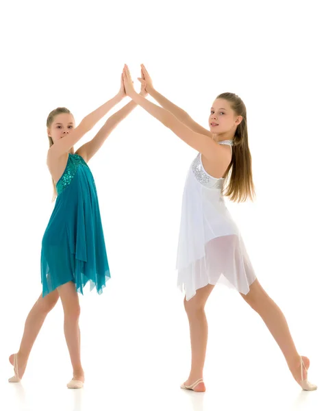 Zwei Schwestern in Sportkleidern tanzen im Studio auf weißem Hintergrund. — Stockfoto