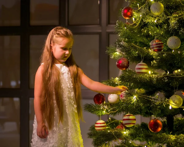 Une petite fille décore un sapin de Noël. Concept Nouvel An, vacances en famille. — Photo