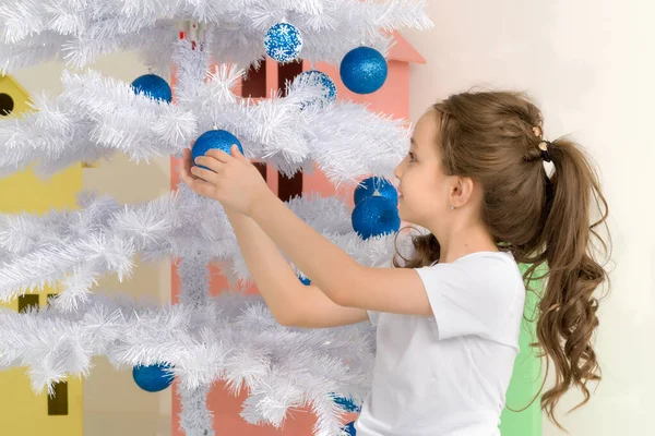 Fille posant à côté de blanc arbre de Noël tenant Bauble — Photo