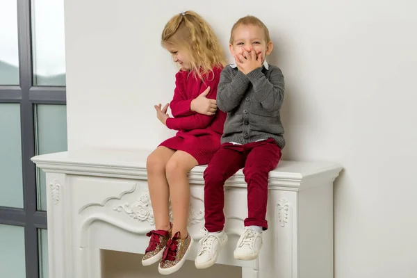 Lindo feliz chico y chica sentado juntos en mantelpiece — Foto de Stock