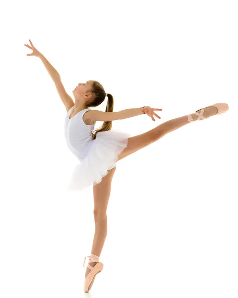 Schattig klein meisje in een tutu en pointe schoenen dansen in de studio op een witte achtergrond. — Stockfoto