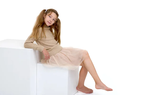 Krásná dívka sedí na bílé kostce — Stock fotografie
