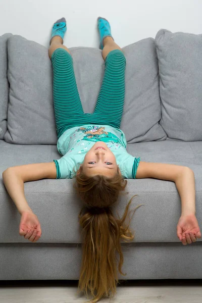 Menina deitada de cabeça para baixo no sofá — Fotografia de Stock