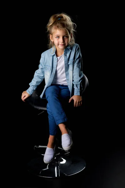 Linda chica rubia sonriente sentada en la silla alta en el estudio — Foto de Stock