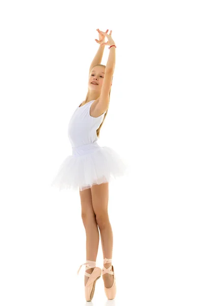 Linda niña en un tutú y zapatos puntiagudos bailando en el estudio sobre un fondo blanco. — Foto de Stock